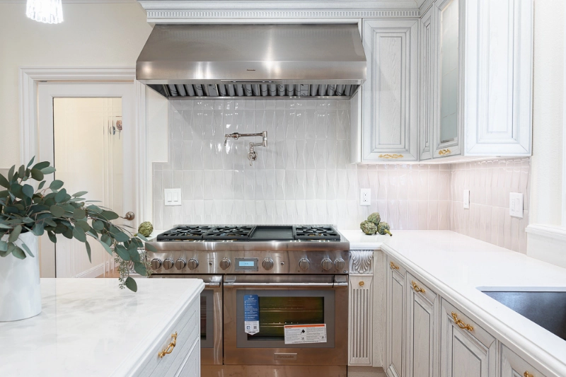 A modern kitchen featuring a stainless steel oven, stove, and white cabinets.