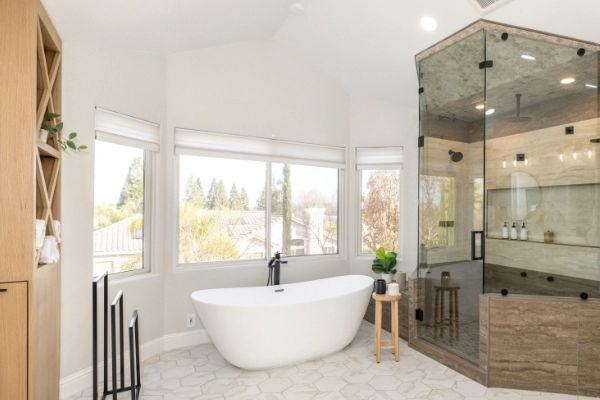 Bright bathroom featuring a freestanding bathtub, large windows, and a glass-enclosed shower.