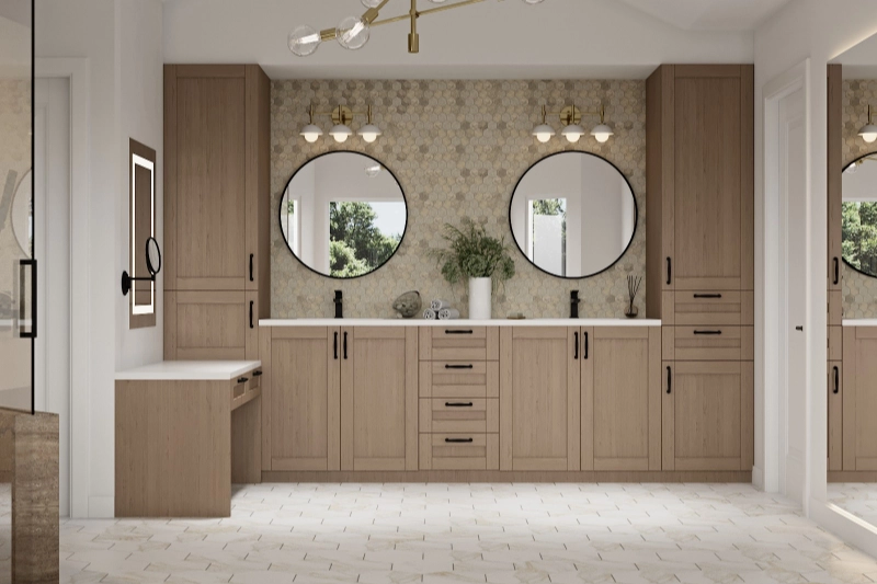 A bathroom with two round mirrors above a double vanity with wooden cabinets, a small makeup station on the left, and hexagonal tile backsplash, crafted to perfection by expert home remodelers.