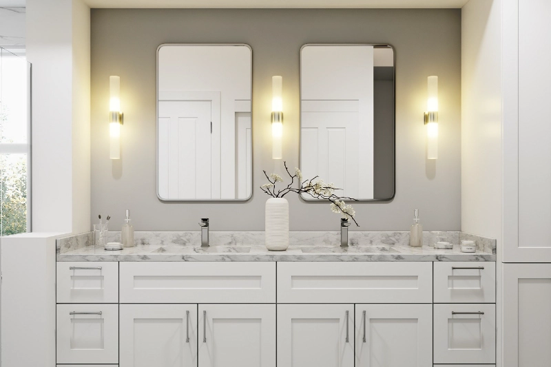 A Regency bathroom remodel showcases a double-sink vanity with marble countertops, two rectangular mirrors, and wall-mounted light fixtures. A white vase with branches sits elegantly between the sinks.