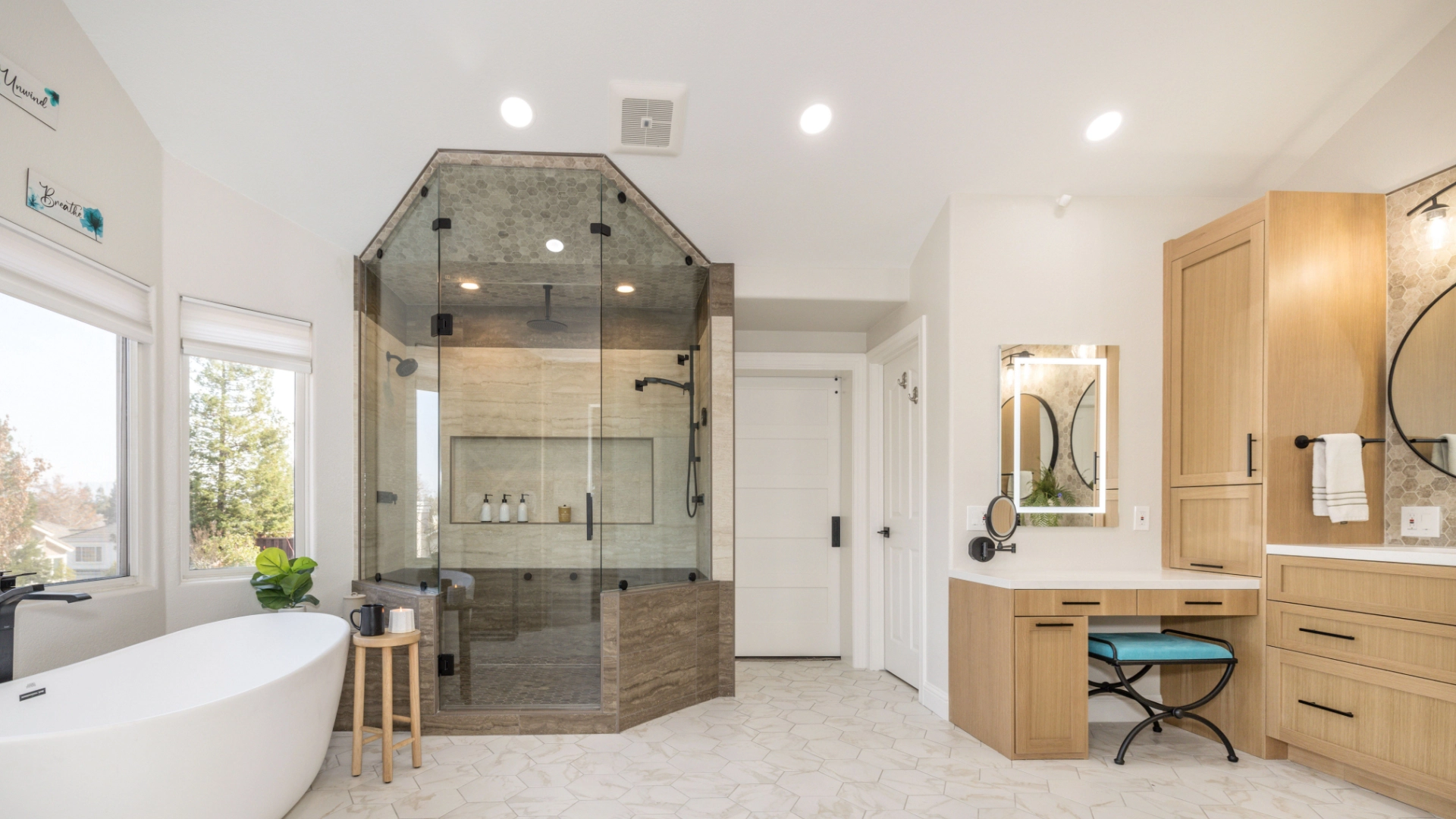 Modern bathroom with a glass-enclosed shower, freestanding bathtub, vanity with mirrors, and light wooden cabinetry.